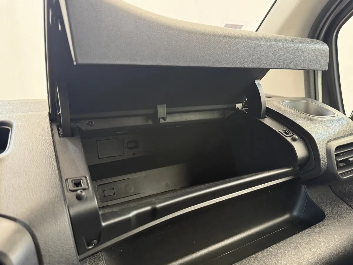 Vue rapprochée de la boîte à gants ouverte côté passager dans l'habitacle noir du Toyota Proace City blanc.