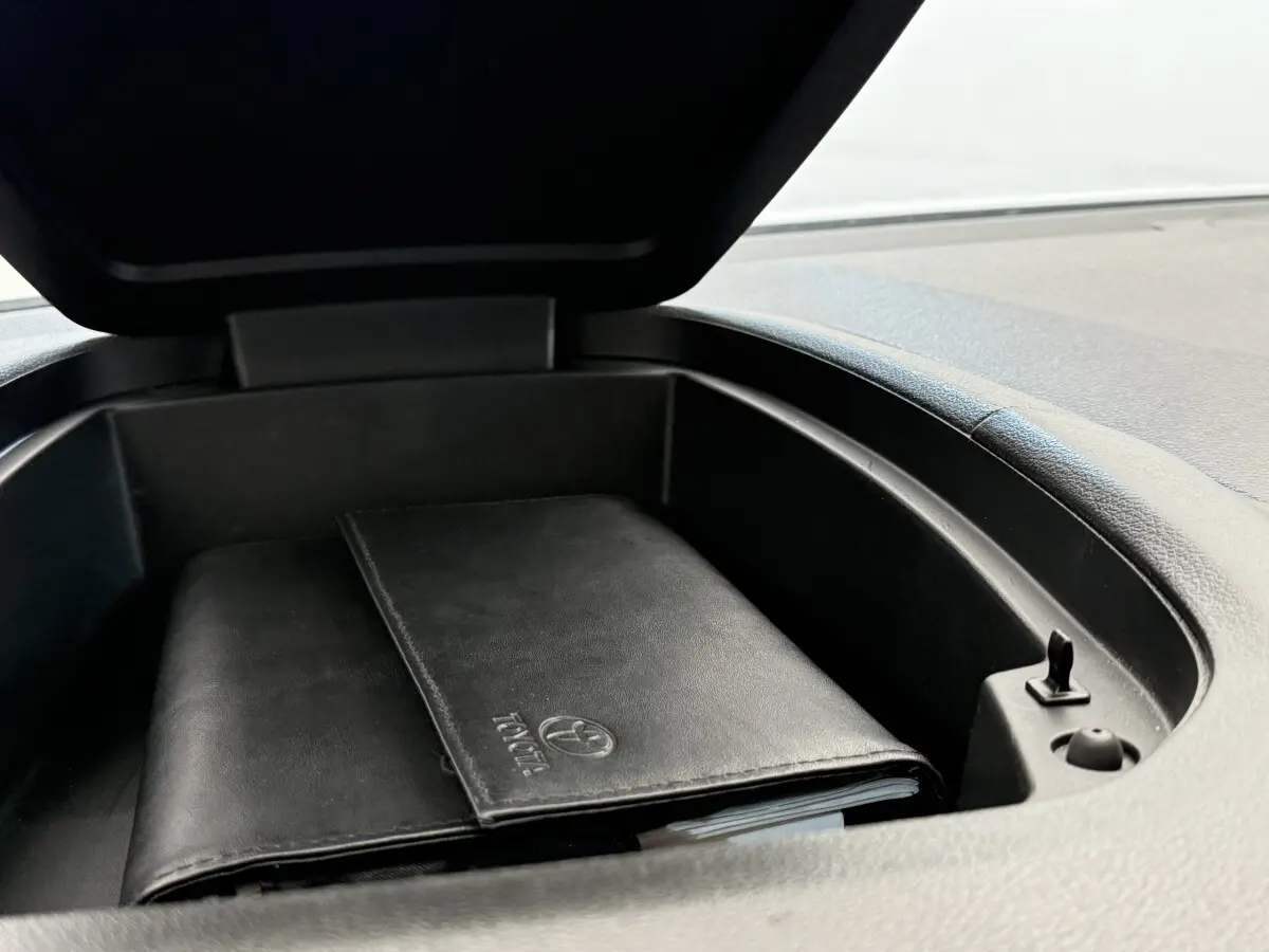 Coffre de rangement ouvert sur le tableau de bord d’un Toyota Proace City blanc, avec un porte-documents noir à l’intérieur.