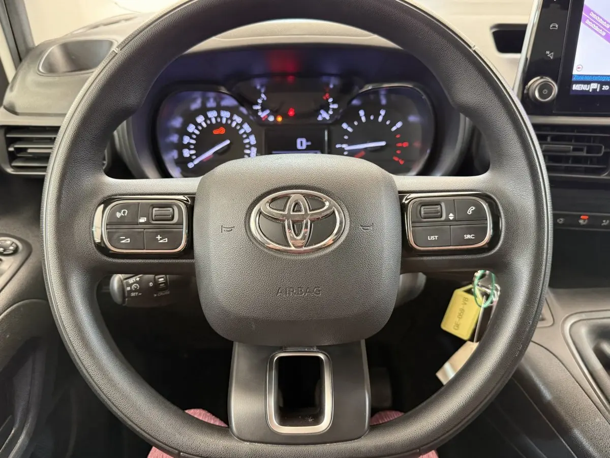 Vue rapprochée du volant multifonctions noir de la Toyota Proace City 2022 avec tableau de bord et écran tactile visible à droite.