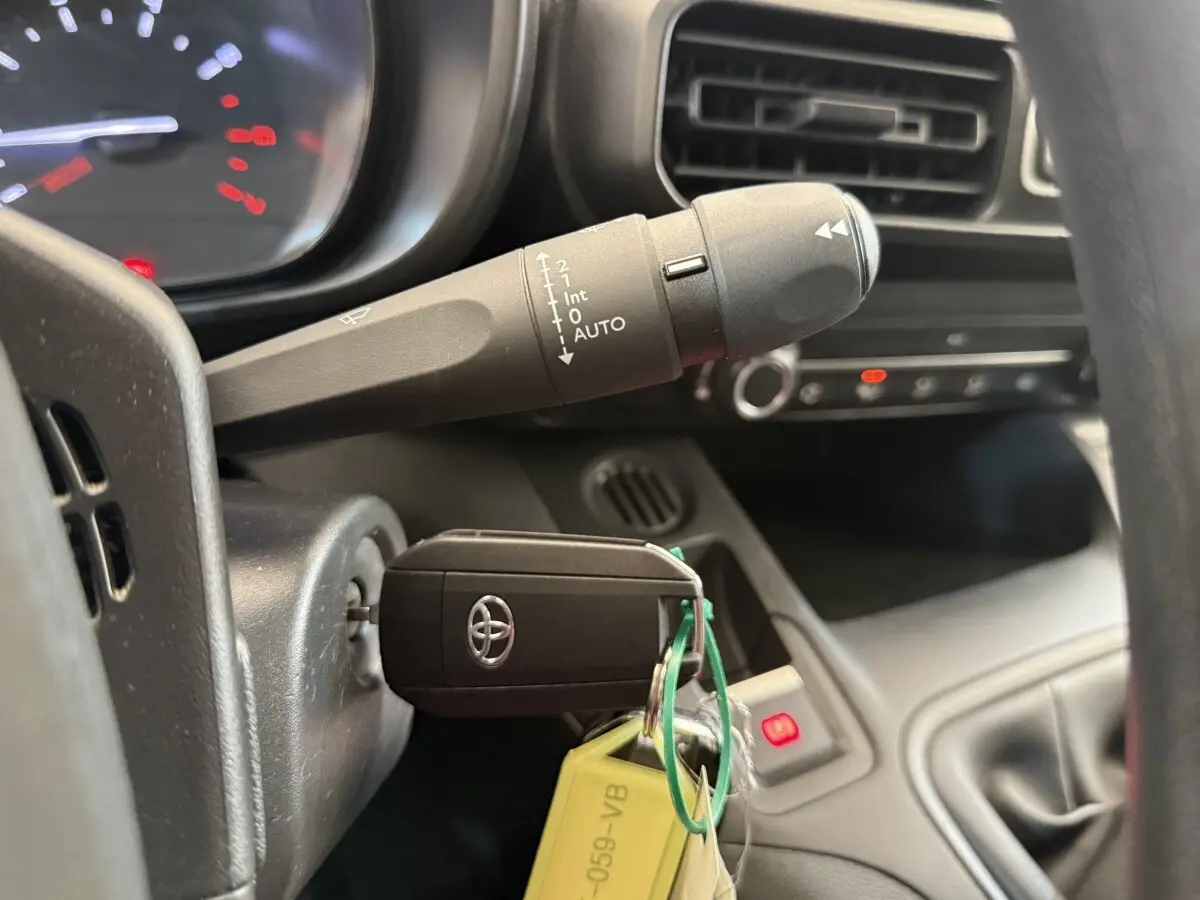 Gros plan intérieur sur la clé Toyota insérée dans le contact, avec commande d’essuie-glace et partie du tableau de bord visible.