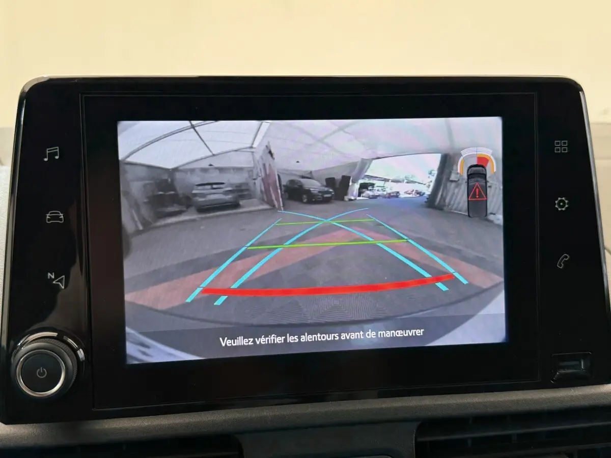 Écran tactile montrant la caméra de recul avec guidage et alertes de proximité du Toyota Proace City blanc.