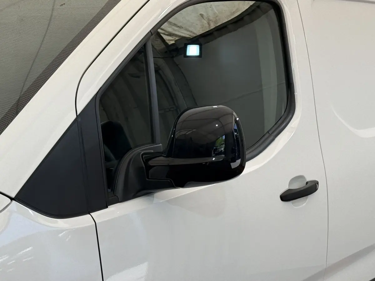 Vue rapprochée du côté gauche blanc du Toyota Proace City 2022, mettant en valeur le rétroviseur noir brillant et la poignée de porte.
