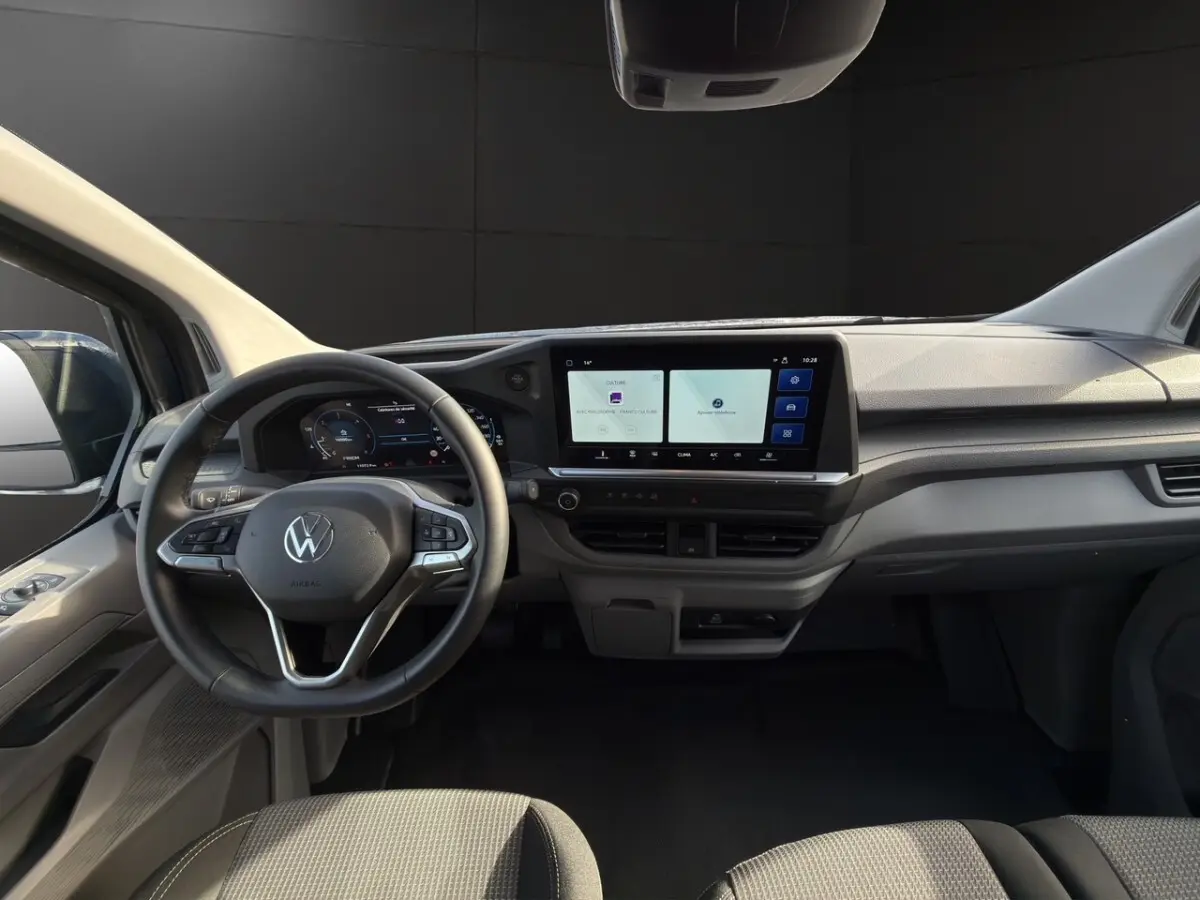 Vue intérieure du tableau de bord du Volkswagen Transporter 2025, avec volant multifonctions et écran tactile central large.
