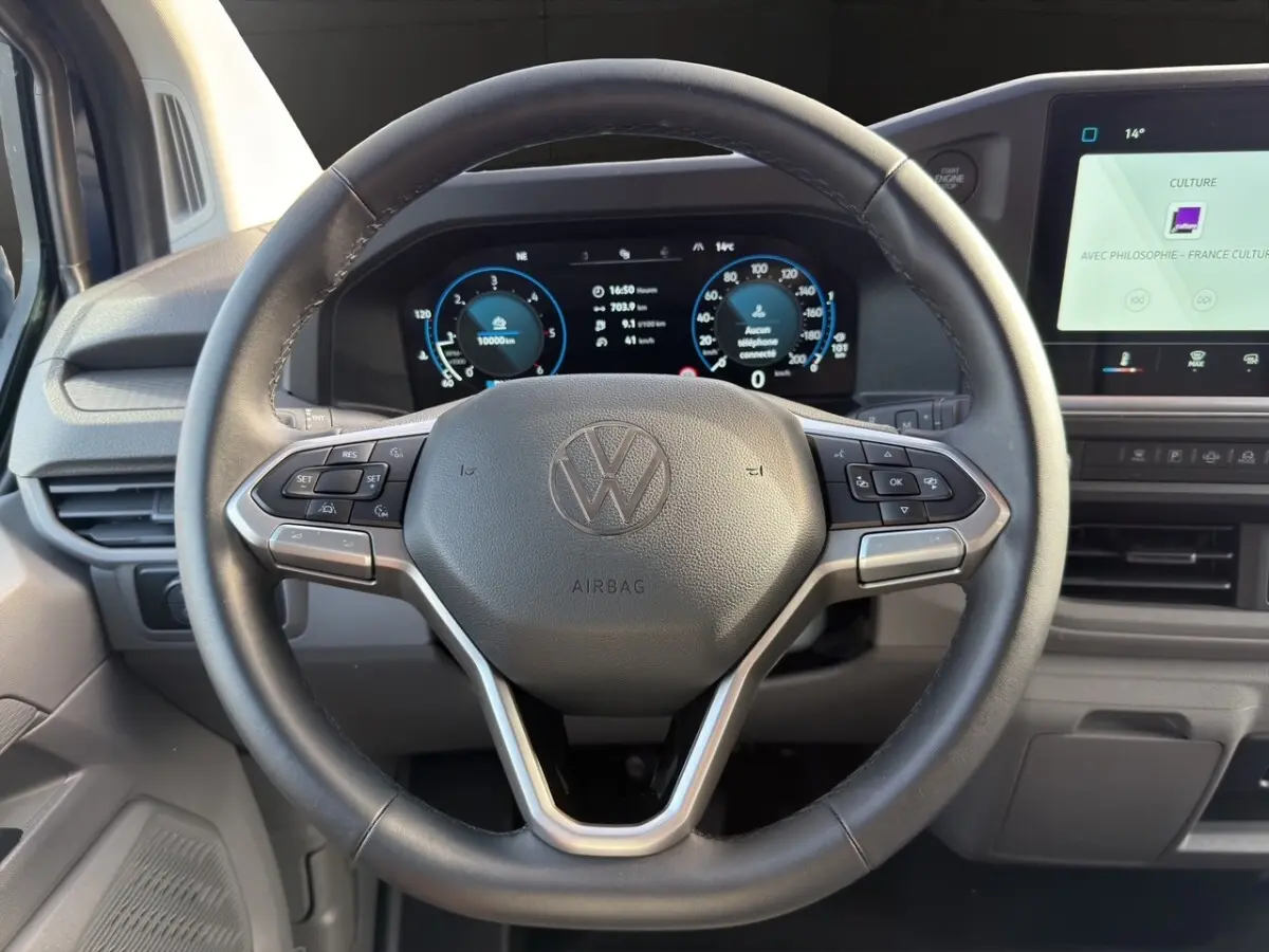 Vue intérieure centrée sur le volant noir du Volkswagen Transporter 2025 avec tableau de bord digital et écran tactile.