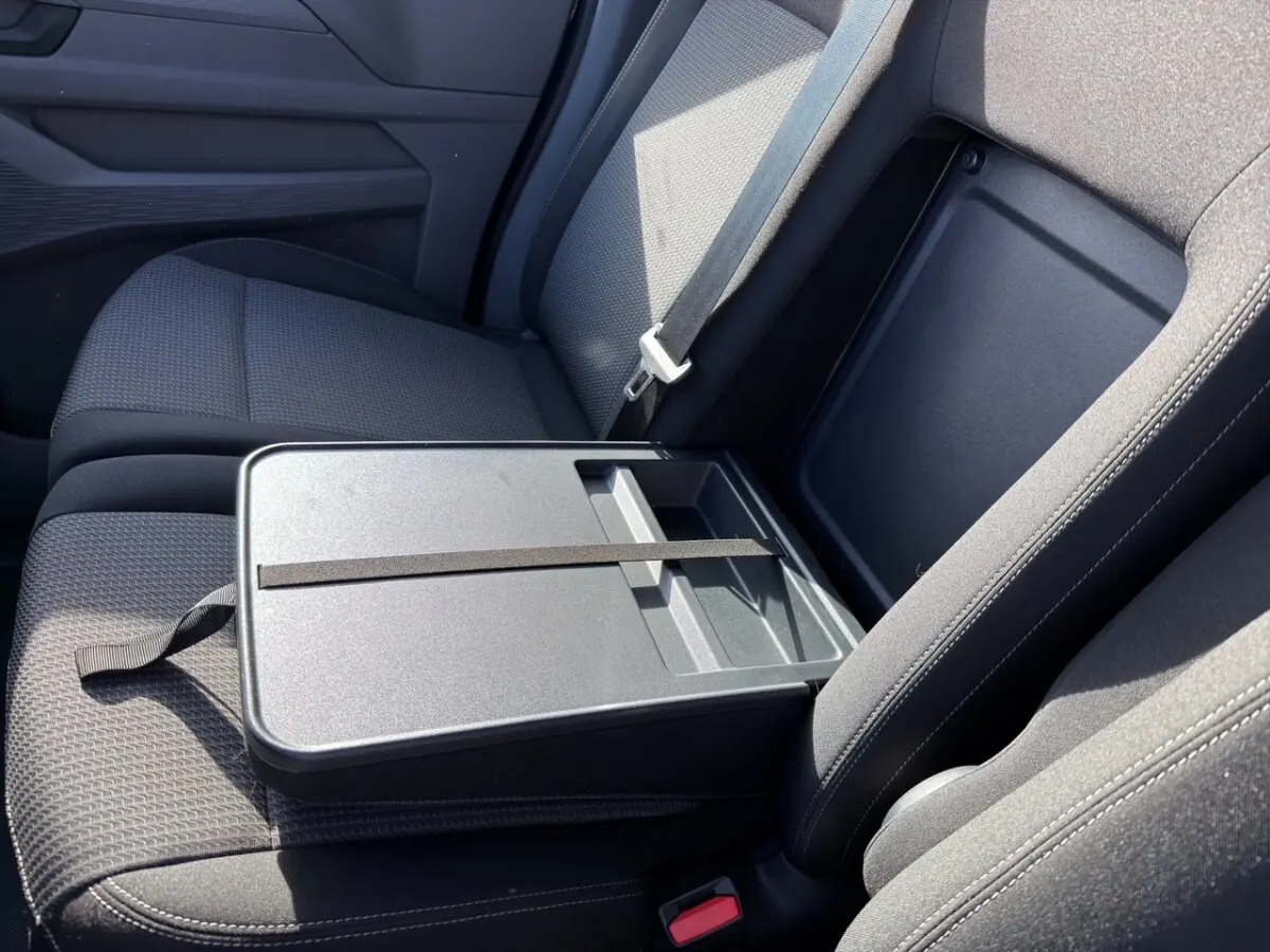 Vue rapprochée de l'intérieur côté passager du Volkswagen Transporter 2025, siège gris avec tablette repliable.