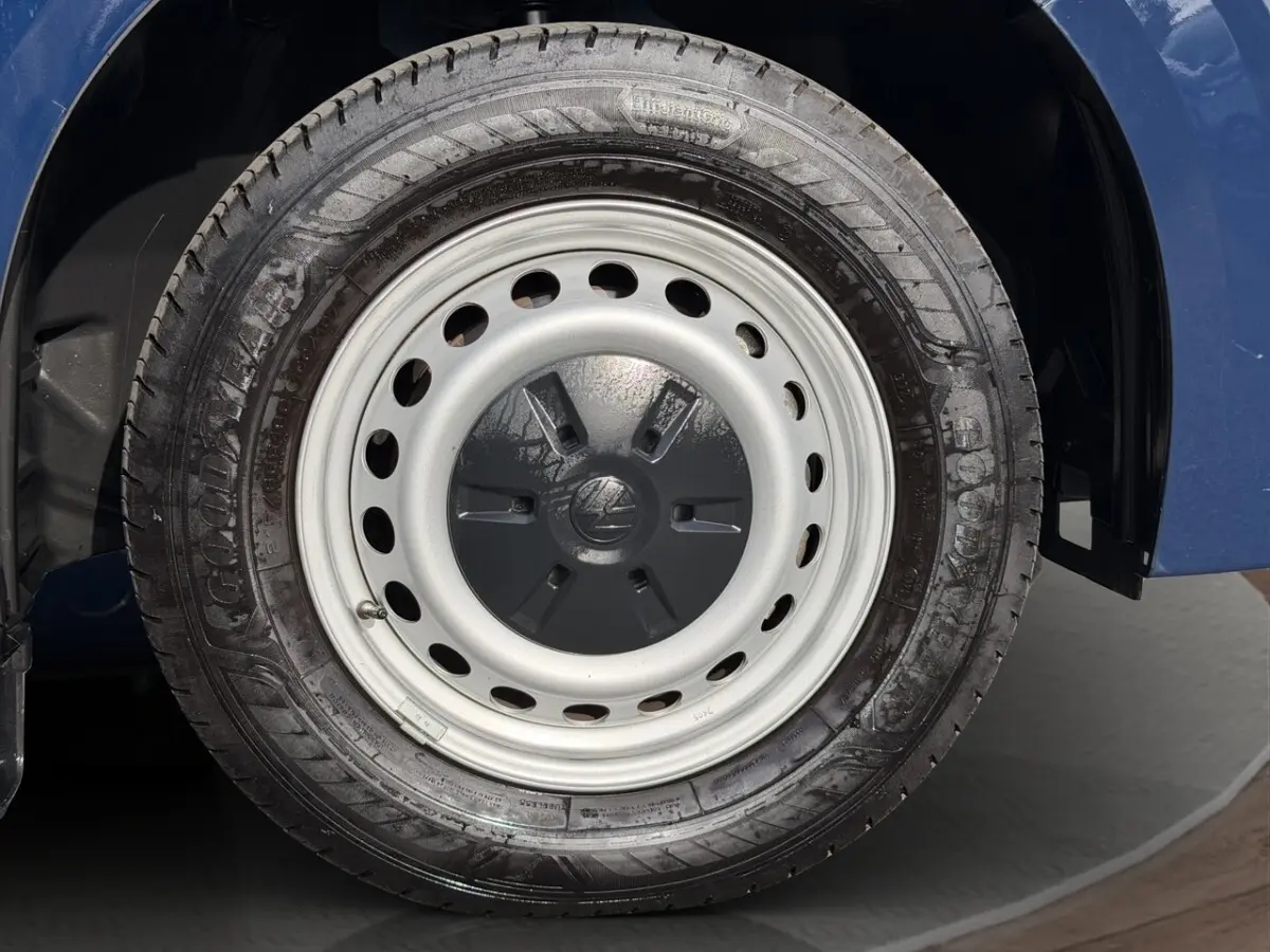 Gros plan sur la roue arrière droite en jante acier du Volkswagen Transporter bleu 2025.