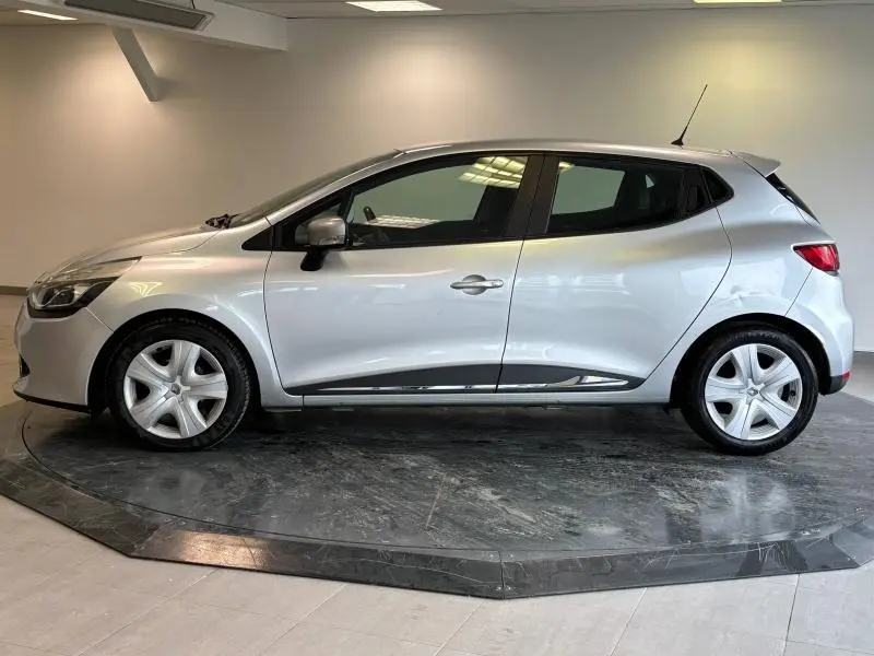 Profil droit d'une Renault Clio gris platine de 2014, compacte et élégante, sur fond neutre intérieur.