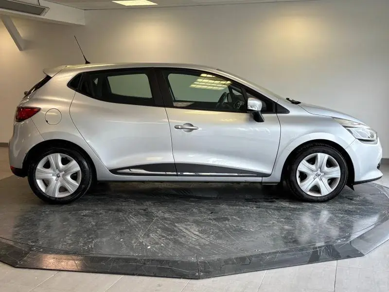 Profil droit d'une Renault Clio gris platine de 2014, avec jantes alu et vitres teintées, sur fond neutre intérieur.