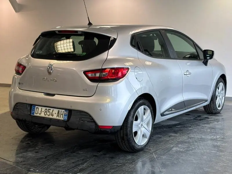 Vue 3/4 arrière droite d'une Renault Clio gris platine de 2014 avec jantes alu et becquet arrière.
