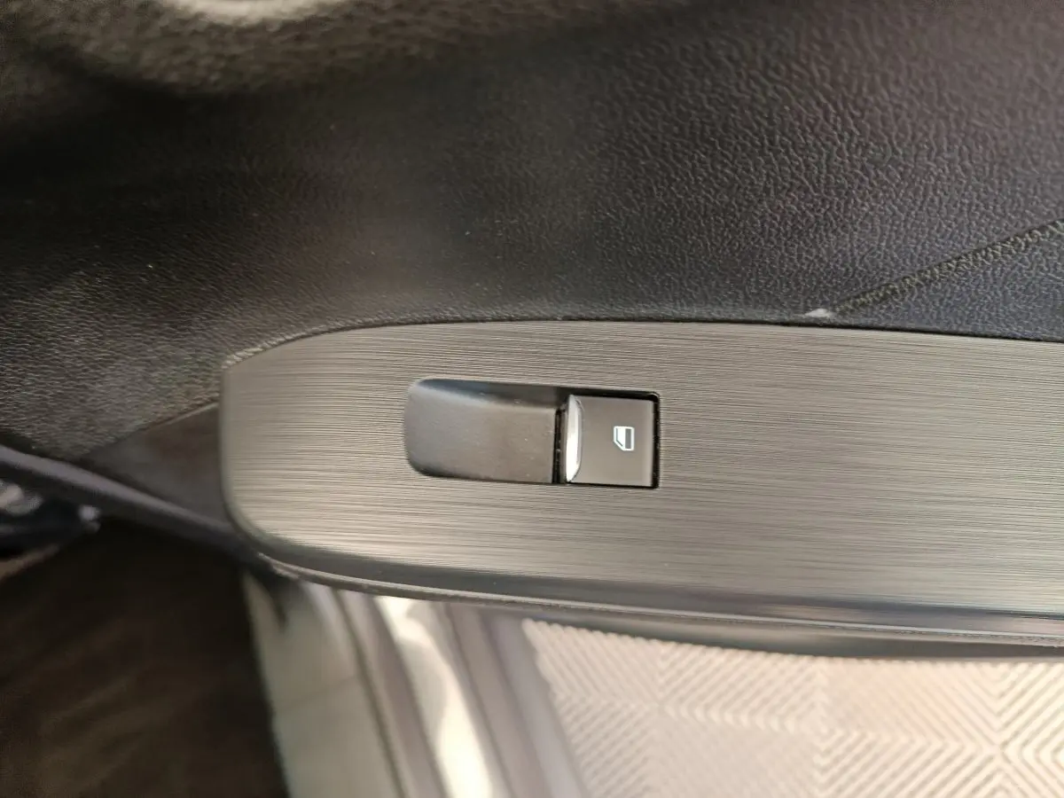 Bouton de commande de lève-vitre côté conducteur sur panneau de porte intérieur noir du Ford Kuga gris clair 2024.