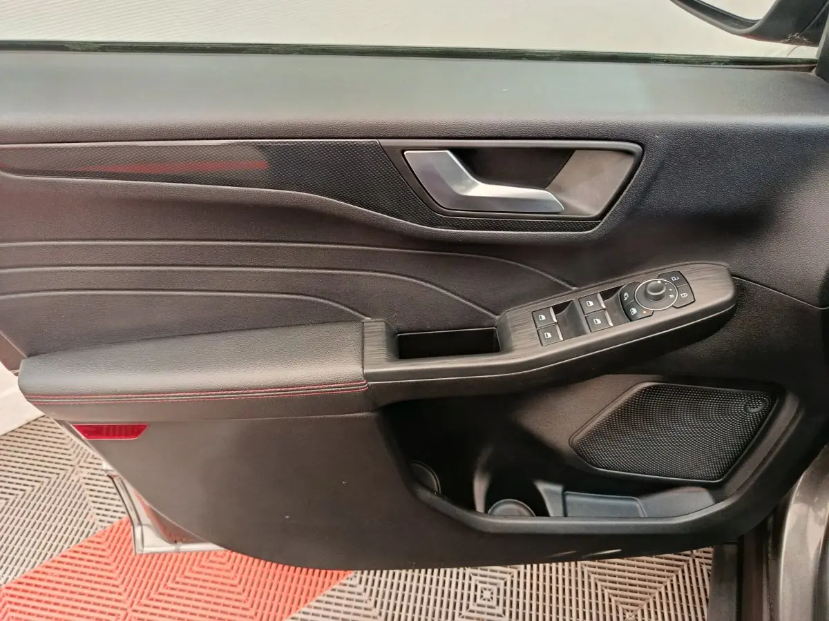 Panneau de porte avant gauche noir avec commandes électriques et surpiqûres rouges du Ford Kuga 2024 St Line.