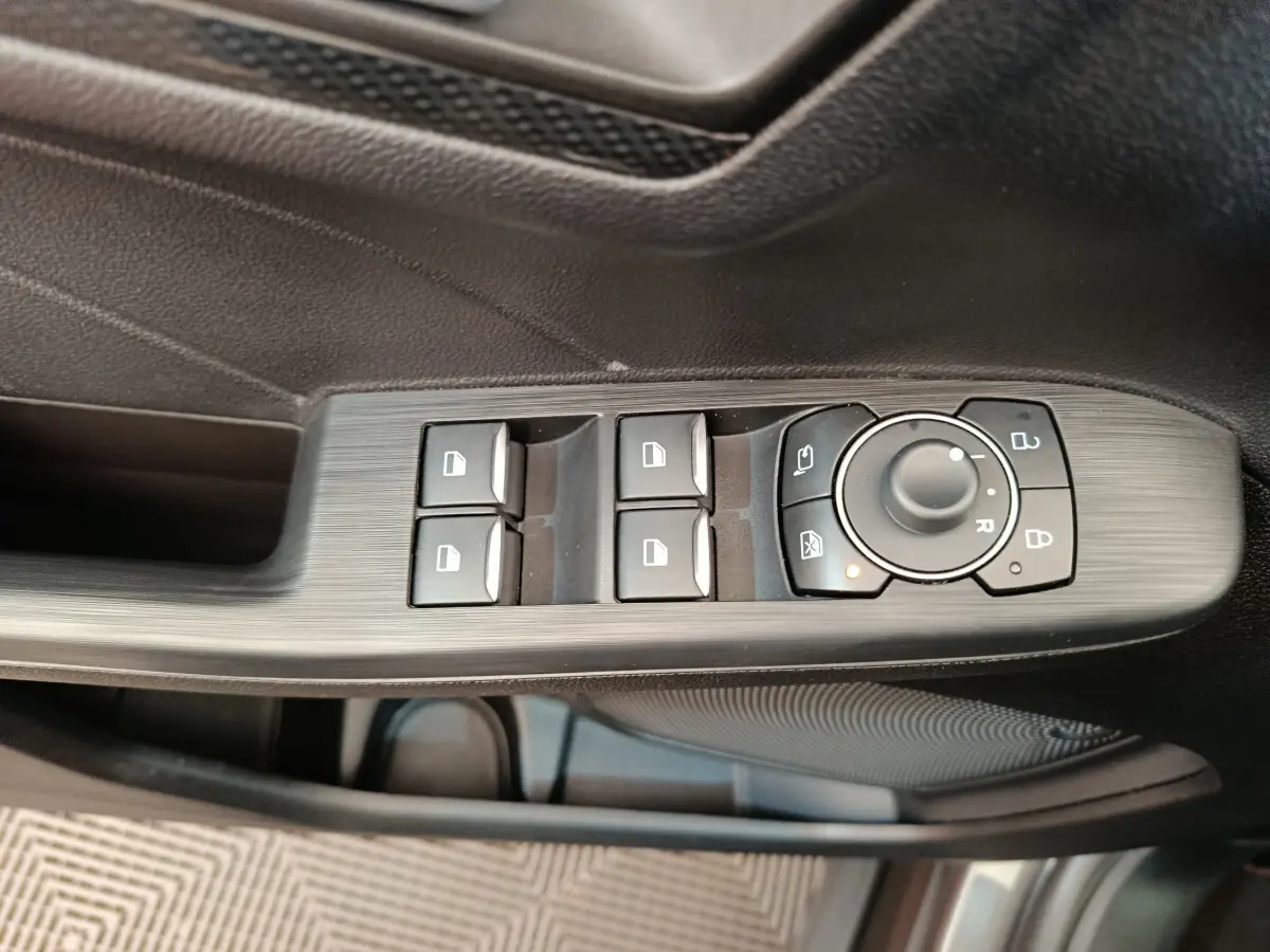 Gros plan sur les commandes de lève-vitres et rétroviseurs côté conducteur du Ford Kuga gris clair 2024.