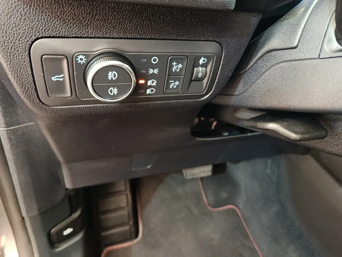 Gros plan sur les commandes d'éclairage et ouverture du coffre côté gauche du tableau de bord du Ford Kuga gris clair 2024.