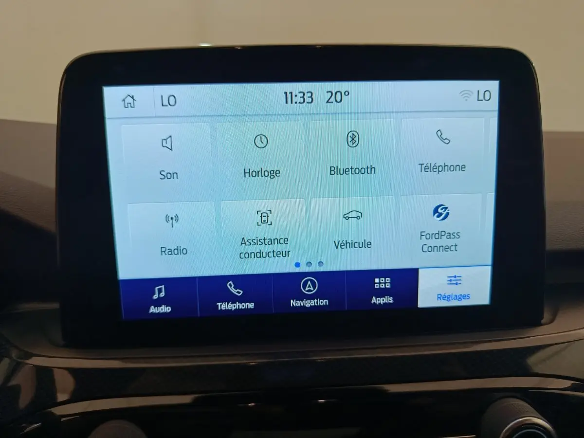 Écran tactile central du tableau de bord du Ford Kuga gris clair 2024 affichant les réglages et options connectées.