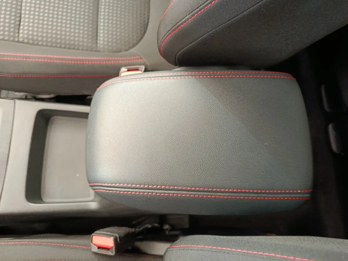 Accoudoir central noir avec surpiqûres rouges, entre les sièges avant du Ford Kuga 2024 St Line.