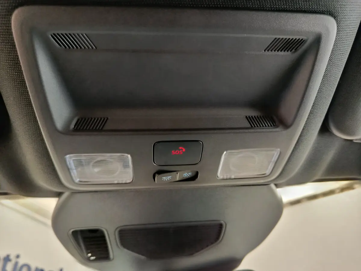Vue en plongée sur le plafonnier noir du Ford Kuga 2024 avec bouton SOS rouge et éclairages intégrés.