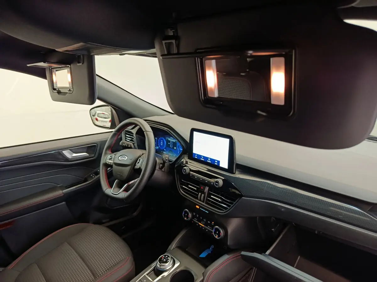 Intérieur du Ford Kuga 2024 St Line, vue côté conducteur, tableau de bord noir avec écran tactile et volant cuir.