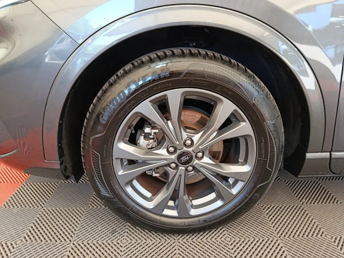 Gros plan sur la roue avant gauche gris clair du Ford Kuga 2.0 EcoBlue 2024 avec jante alliage et pneu Goodyear.