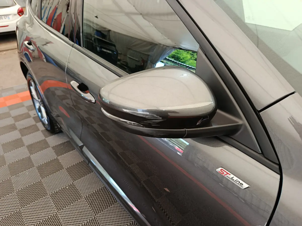 Rétroviseur côté gauche et badge ST Line sur la porte d'une Ford Kuga gris clair vue de profil avant.