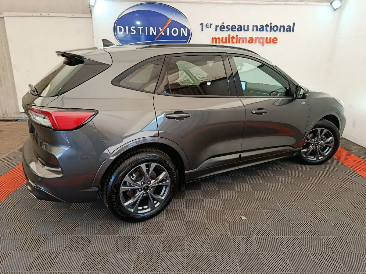 Vue latérale droite du Ford Kuga gris clair 2024 avec jantes alliage et vitres teintées en showroom.