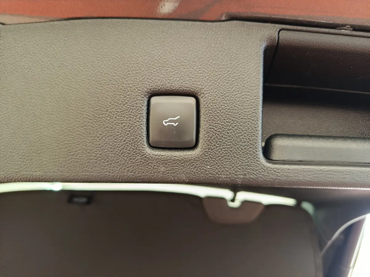 Bouton d'ouverture électrique du coffre sur la garniture intérieure du hayon du Ford Kuga gris clair 2024.