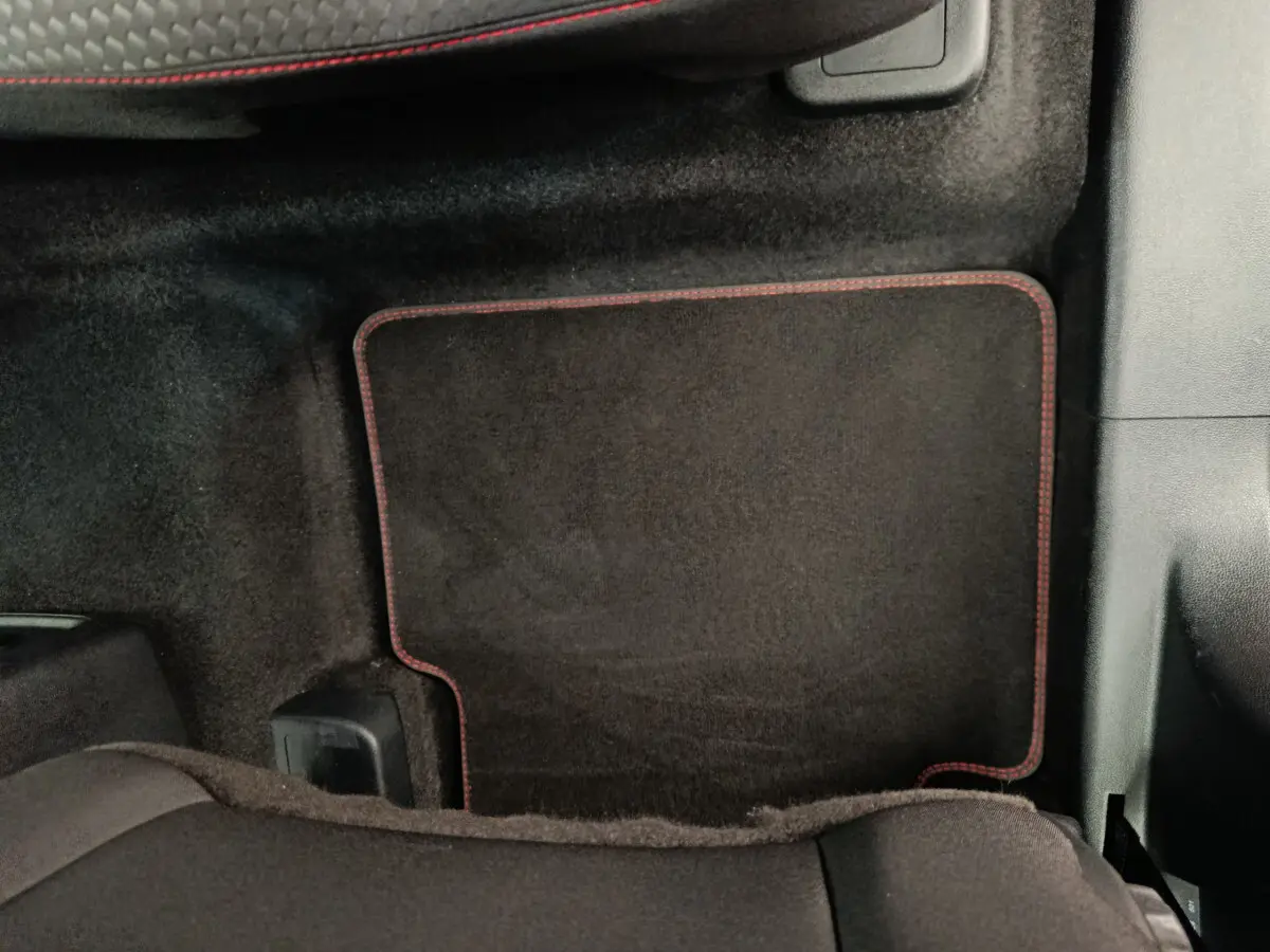 Tapis de sol noir avec surpiqûres rouges côté passager arrière du Ford Kuga gris clair 2024 St Line.