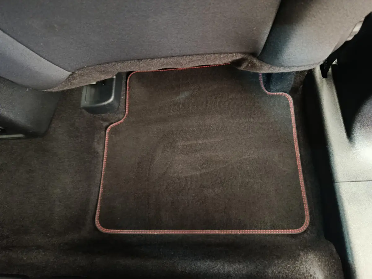 Tapis de sol noir avec surpiqûres rouges sous le siège arrière côté droit du Ford Kuga gris clair 2024 St Line.