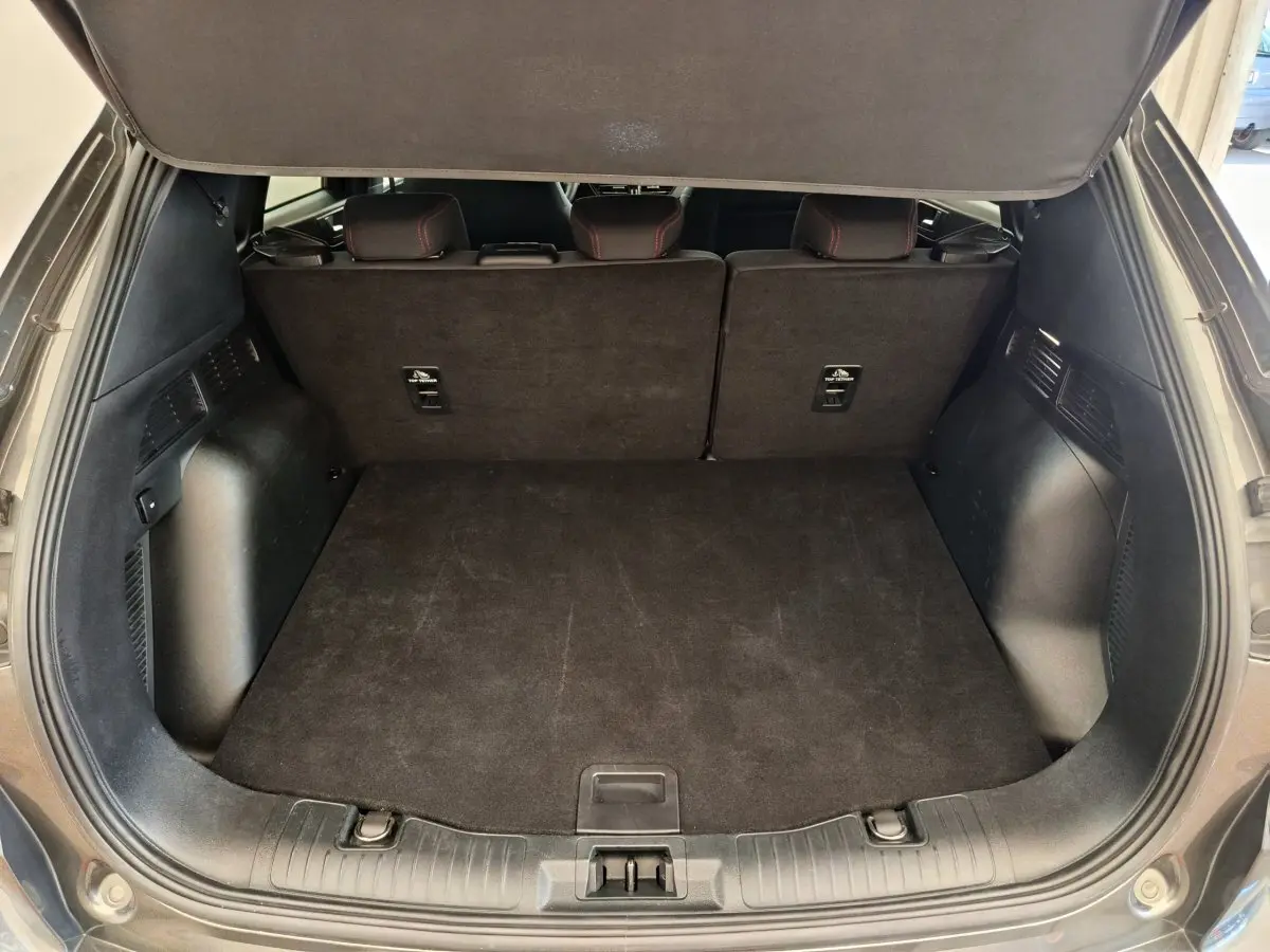 Coffre ouvert vu de l'arrière d'un Ford Kuga gris clair, banquette arrière relevée et espace de chargement vide.