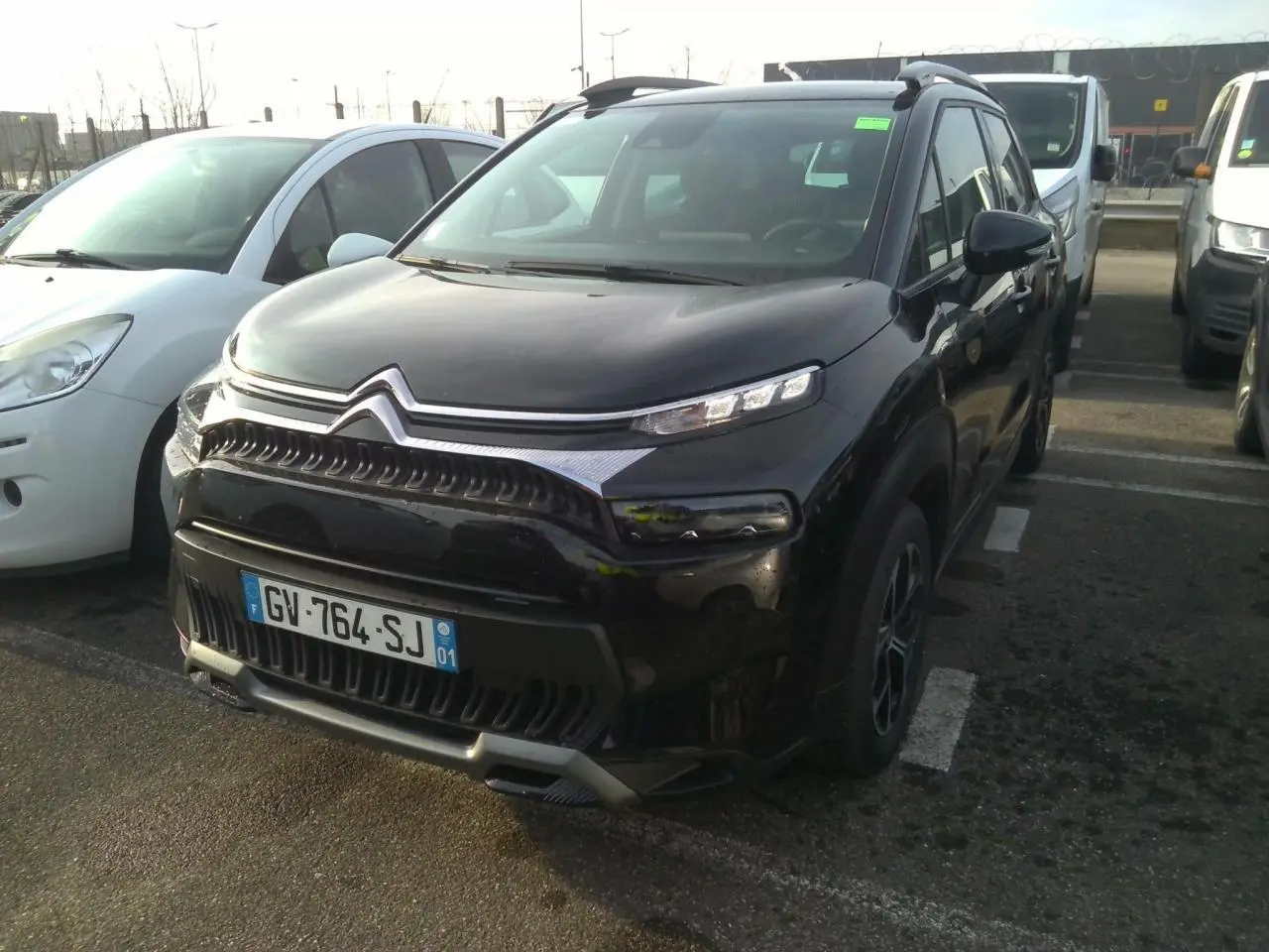 Citroën C3 Aircross noir vue 3/4 avant droit, avec jantes alliage et barres de toit noires brillantes.