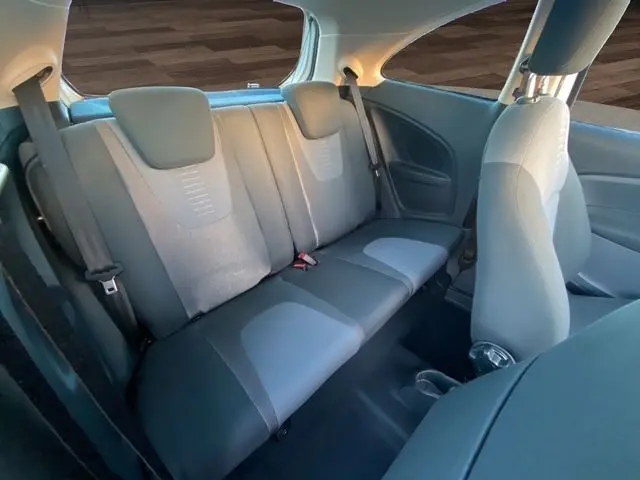 Vue intérieure arrière montrant la banquette grise du Ford KA 1.2 69 TREND blanc de 2015 avec ceintures et appuie-têtes.