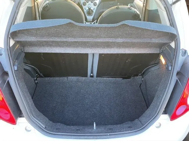 Vue arrière ouverte du coffre d'une Ford Ka blanche 2015, montrant l'intérieur vide et les sièges avant.