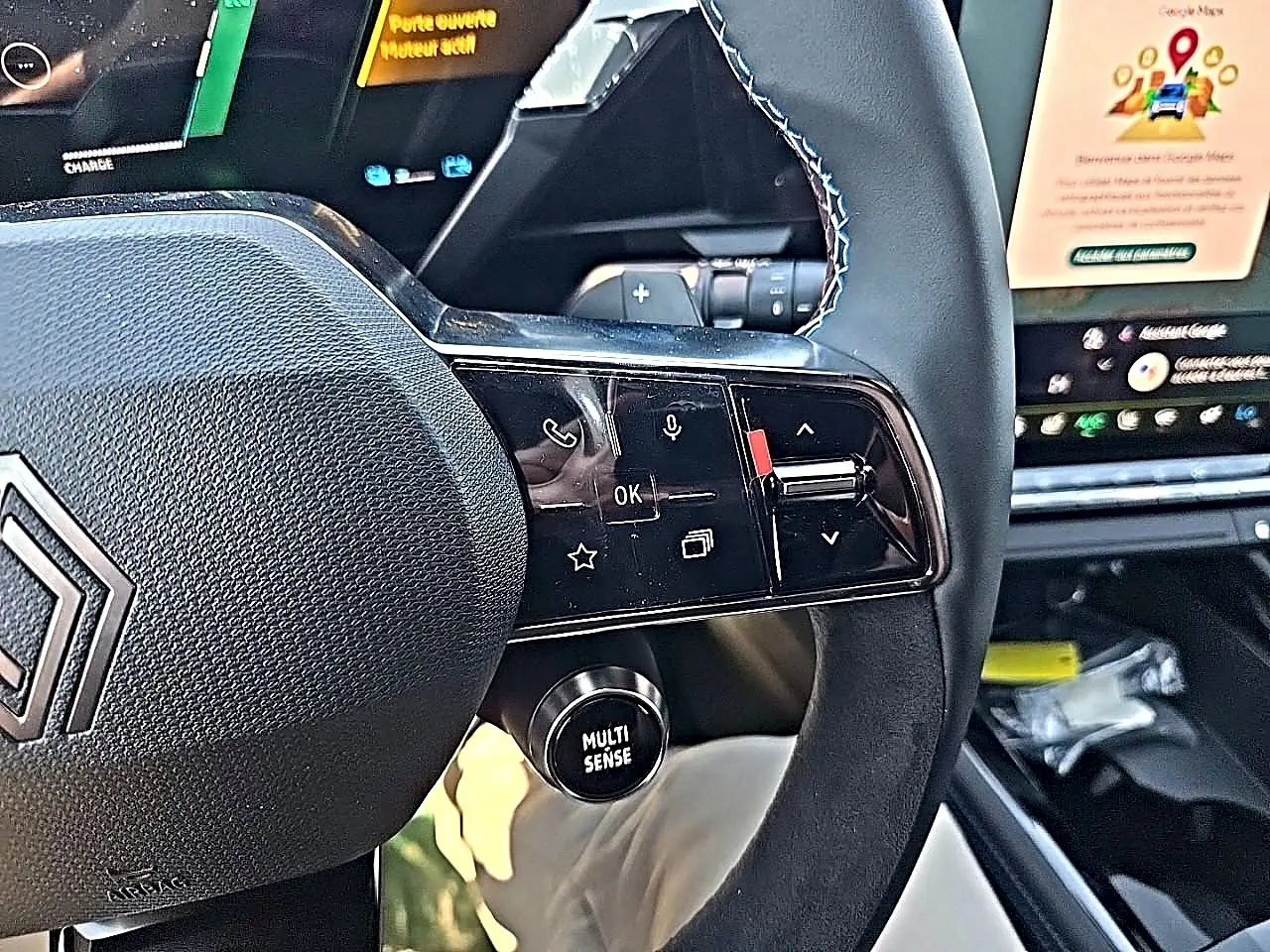Gros plan sur le volant noir du Renault Austral blanc nacré, avec commandes multifonctions et bouton Multi-Sense visible.