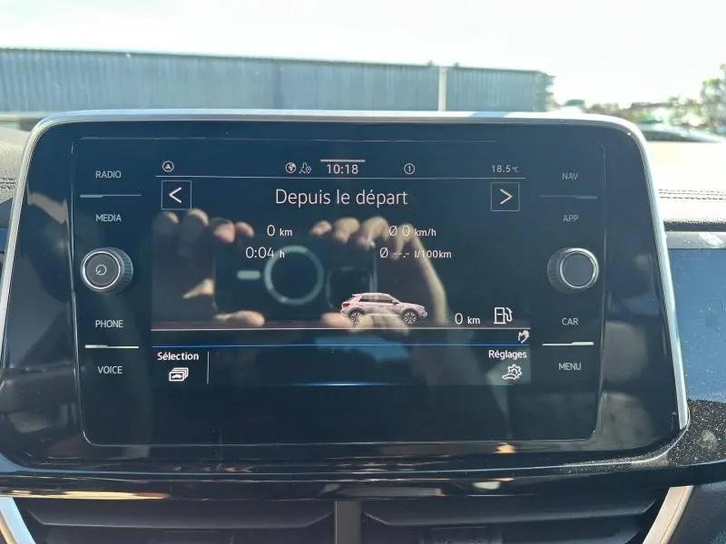 Écran tactile central du Volkswagen T-Roc 2025 affichant les données de trajet, avec reflets visibles.