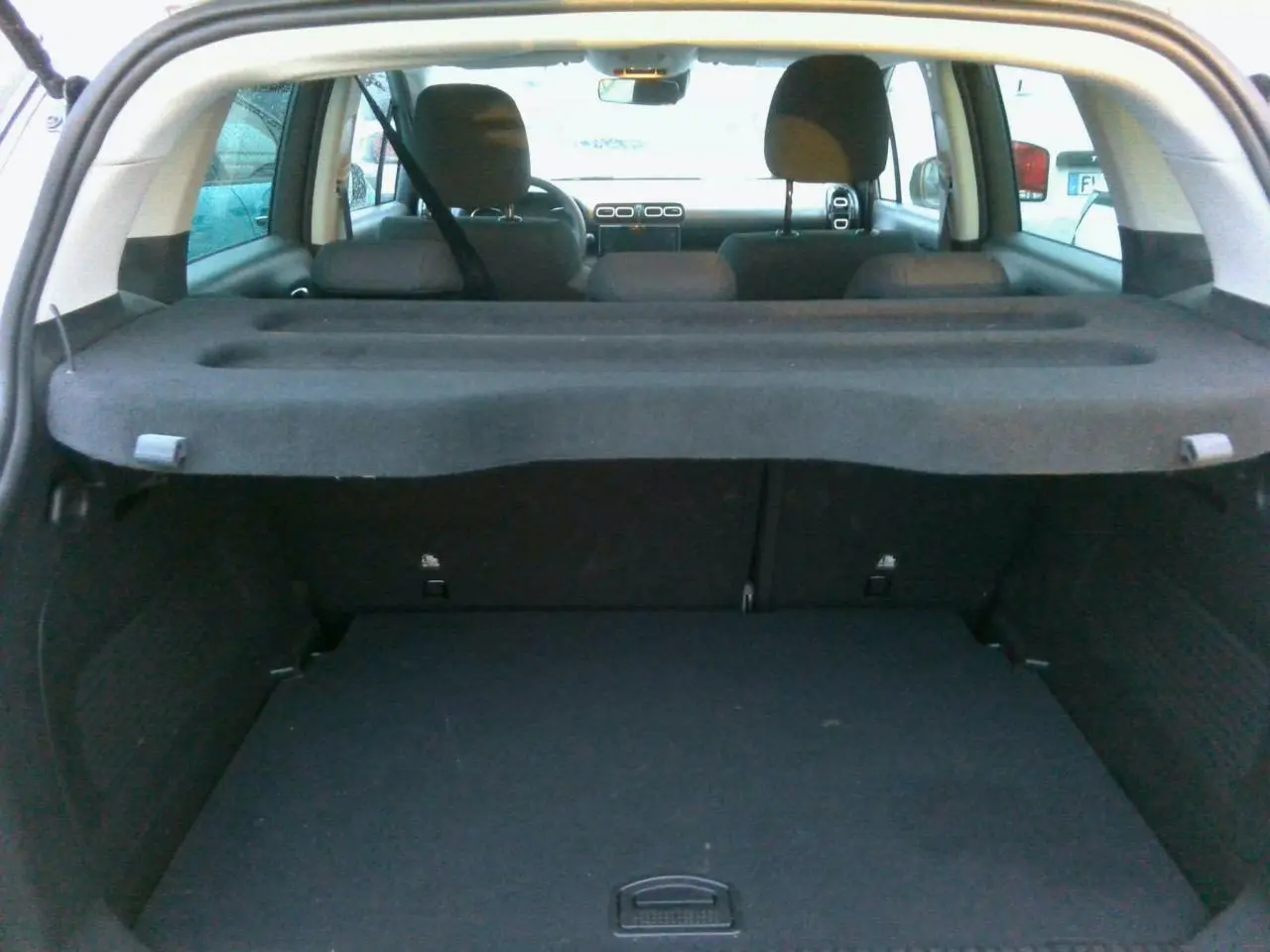 Vue intérieure du coffre et des sièges arrière d'une Citroën C3 Aircross gris foncé, avec tablette cache-bagages déployée.