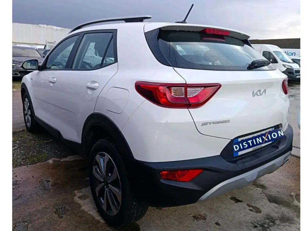 Vue 3/4 arrière droite d’un KIA STONIC blanc 2022 avec feux arrière distinctifs et logo moderne sur le hayon.