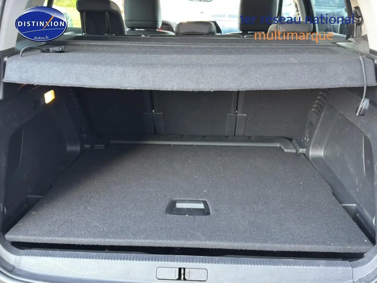 Coffre ouvert vu de l'arrière d'un Citroën C5 Aircross 2025 bleu eclipse, avec cache-bagages en place.