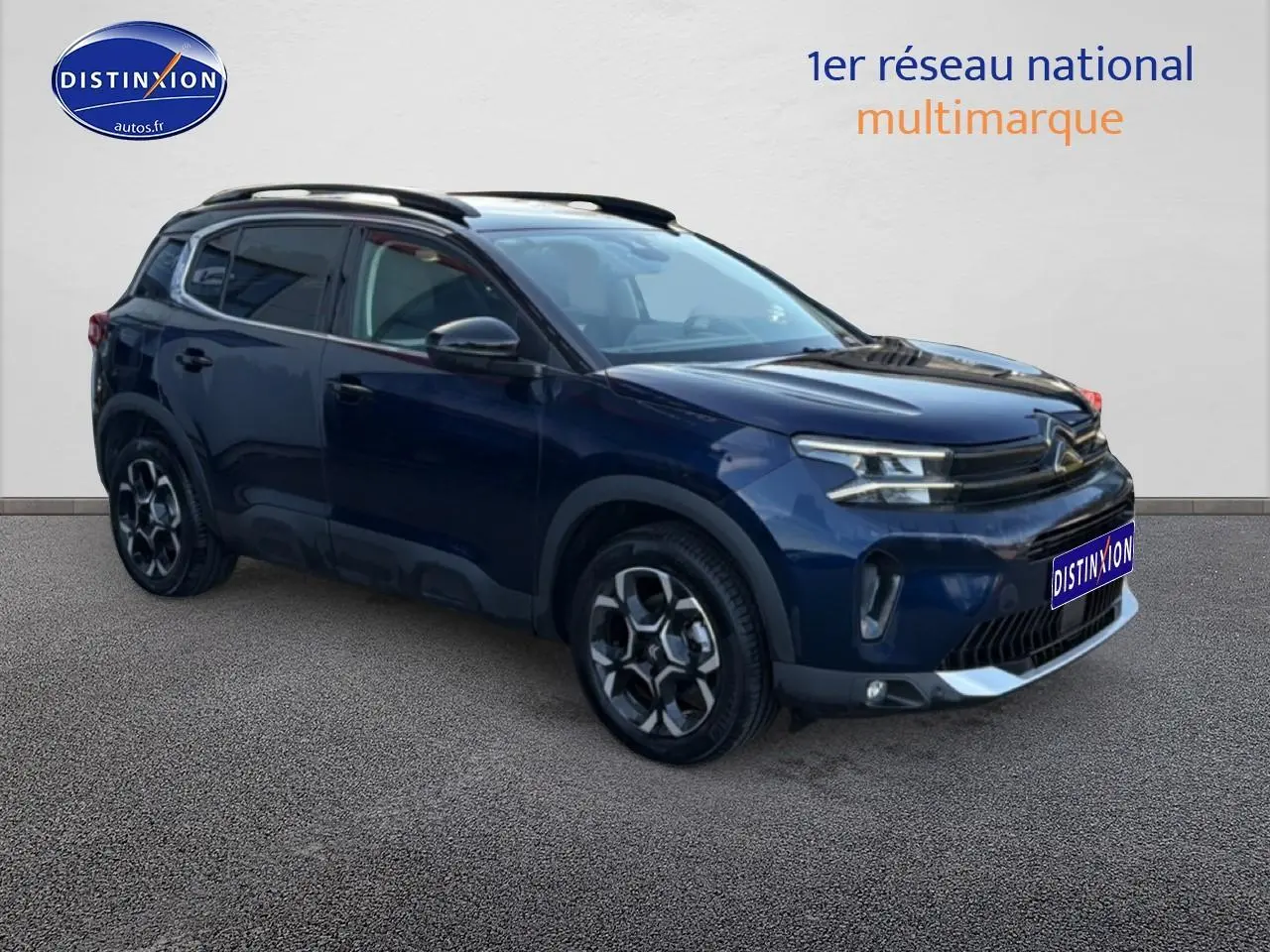 Citroën C5 Aircross bleu eclipse en 3/4 avant droit, avec jantes alu et barres de toit noires visibles.