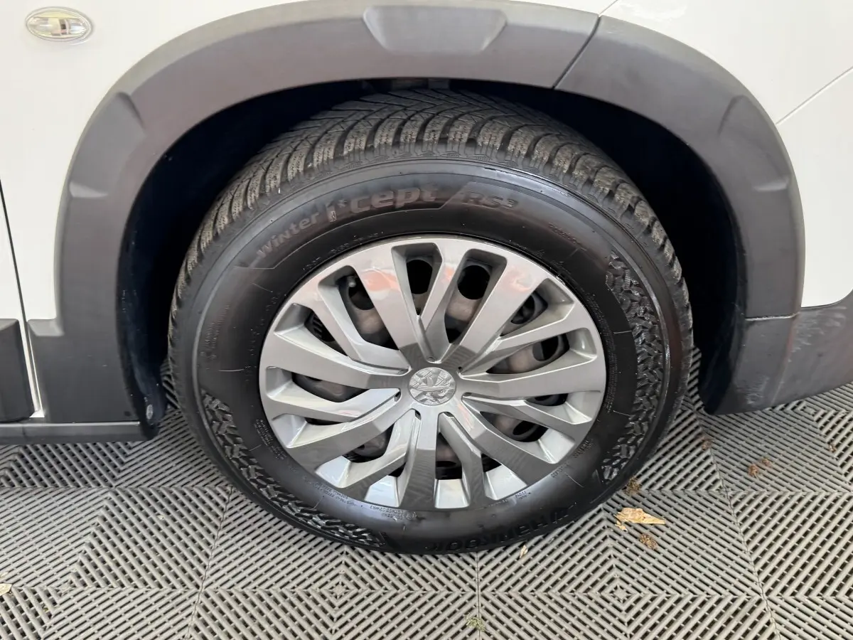 Gros plan sur la roue avant droite d’un Peugeot Rifter blanc, avec jante argentée et pneu hiver marqué "winter i*cept RS2".