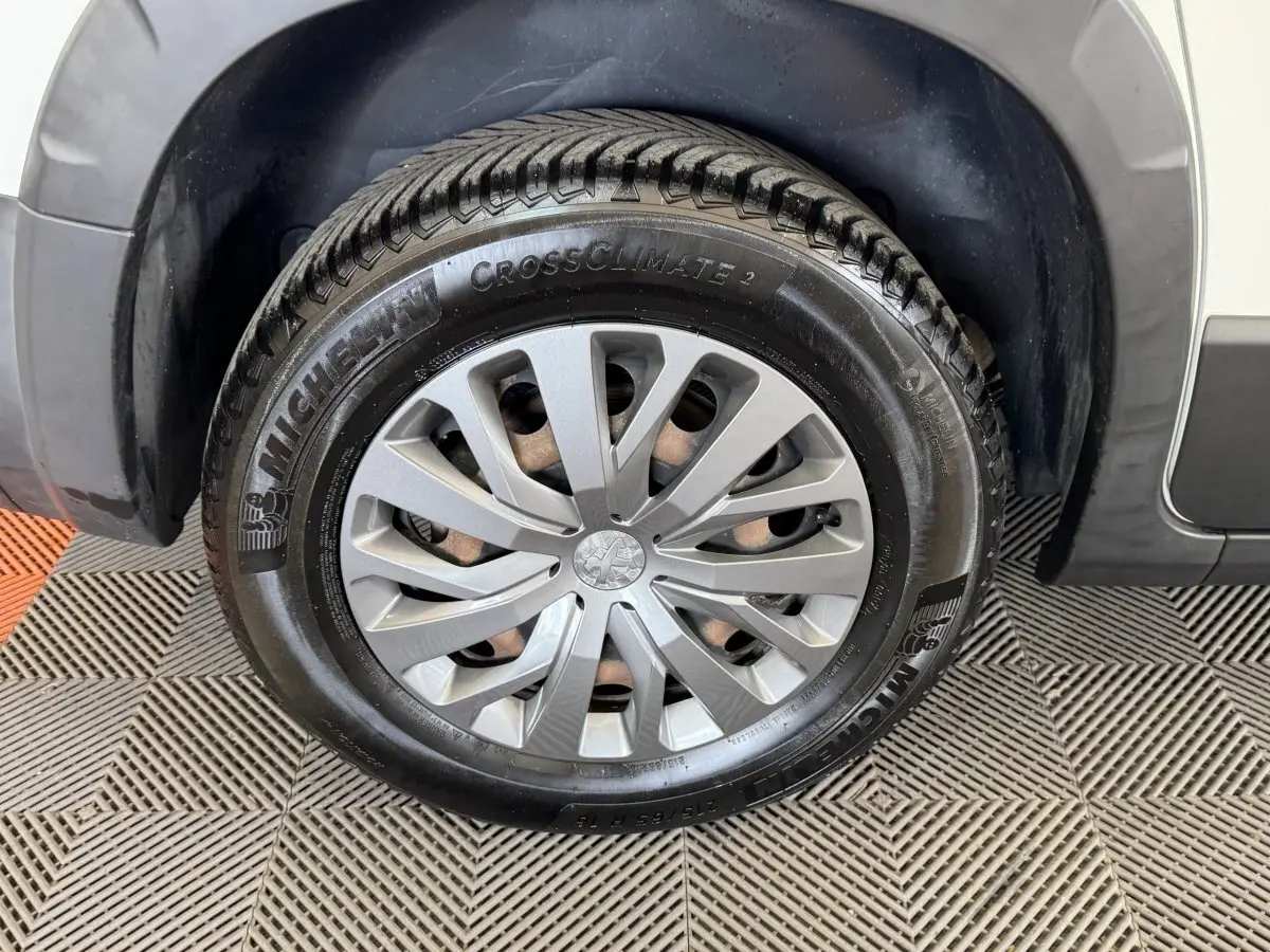 Gros plan sur la roue avant droite du Peugeot Rifter blanc, mettant en valeur la jante et le pneu Michelin CrossClimate 2.