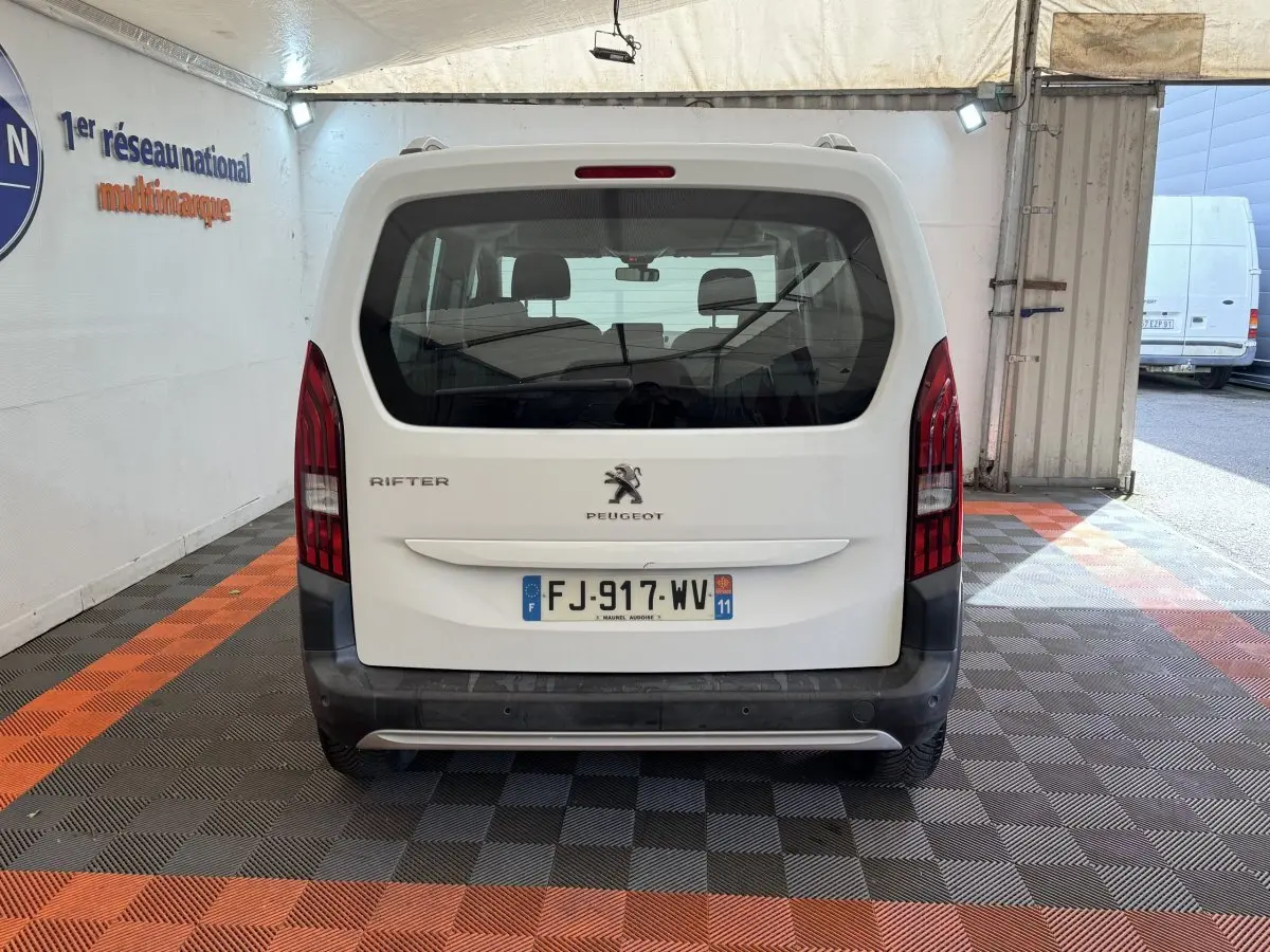 Vue arrière d'un Peugeot Rifter blanc 2019 avec feux verticaux rouges et plaque d'immatriculation française visible.