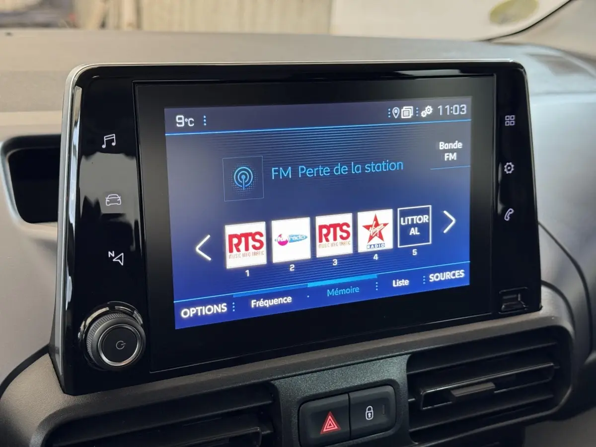 Écran tactile central du tableau de bord du Peugeot Rifter blanc, affichant les stations radio FM.