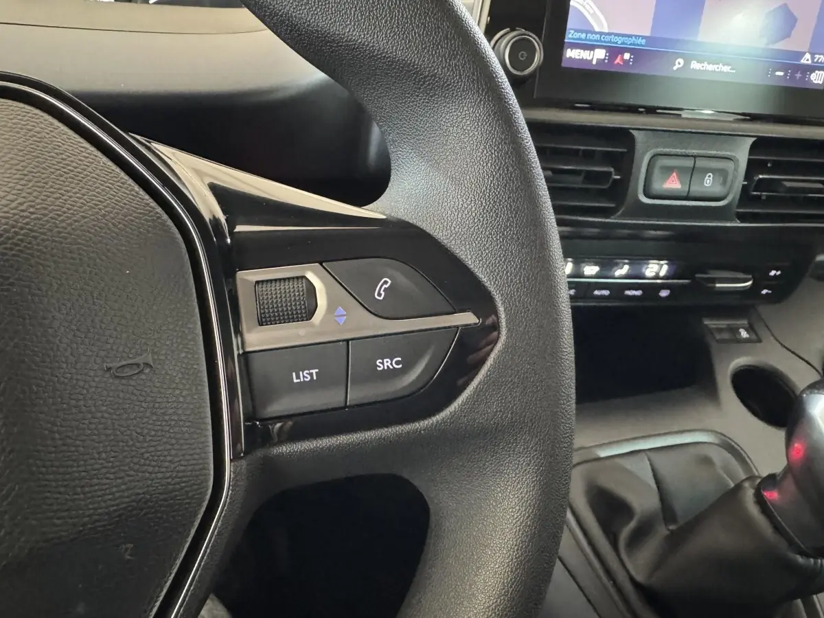 Gros plan sur la partie gauche du volant noir du Peugeot Rifter 2019 avec commandes audio et écran tactile de navigation visible.