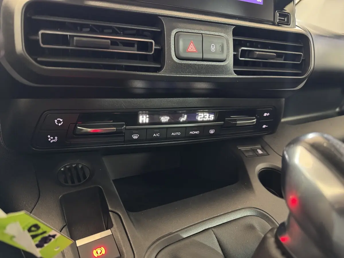 Gros plan sur la console centrale noire du Peugeot Rifter blanc, montrant la climatisation digitale et le frein à main électrique.