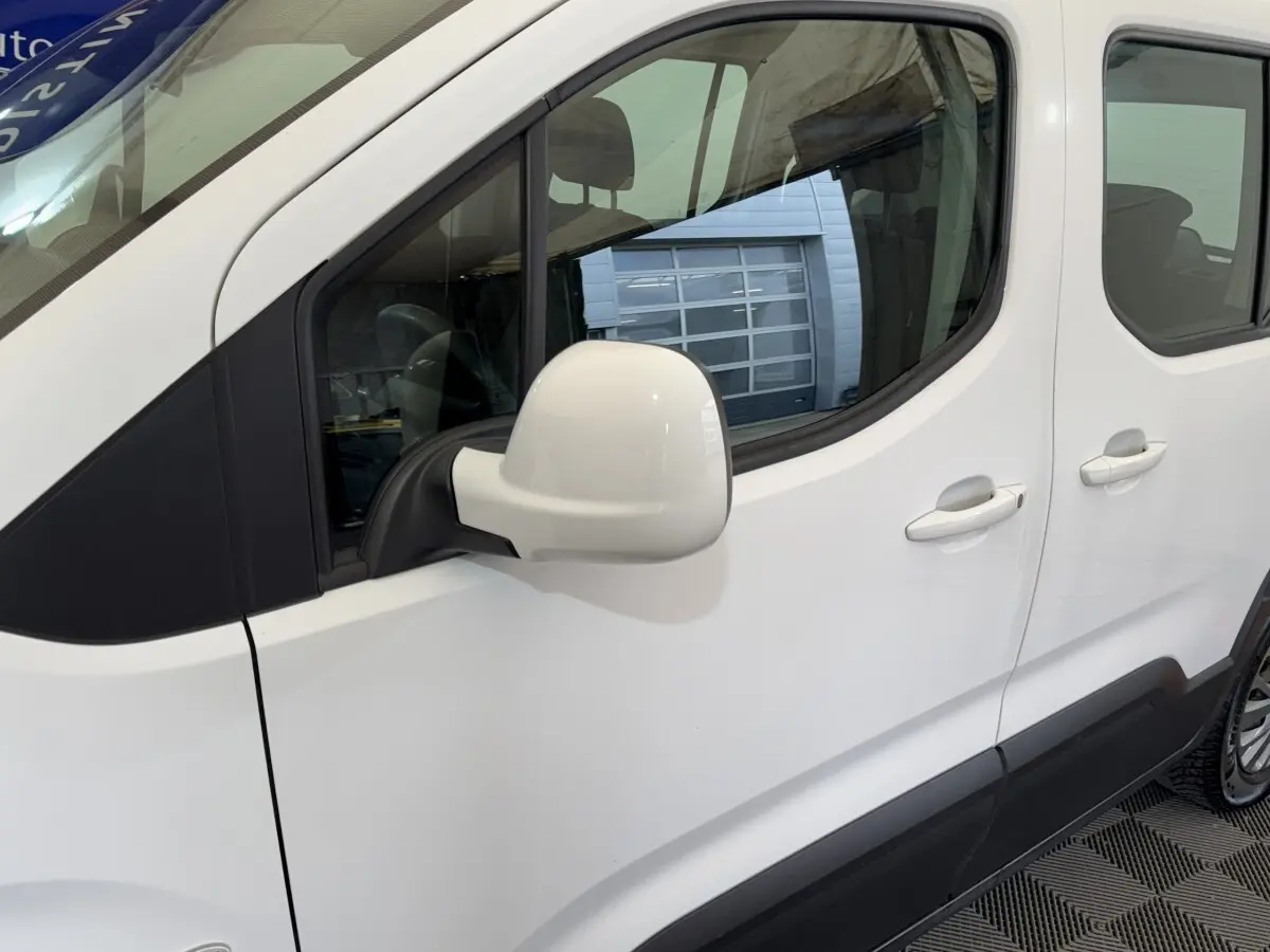 Vue latérale gauche du Peugeot Rifter blanc, mettant en valeur la porte arrière coulissante et le rétroviseur blanc.