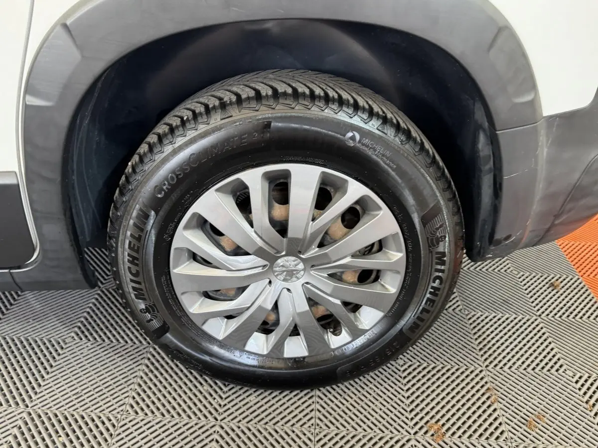 Gros plan sur la roue avant droite blanche du Peugeot Rifter 2019 avec jante argentée et pneu Michelin CrossClimate.