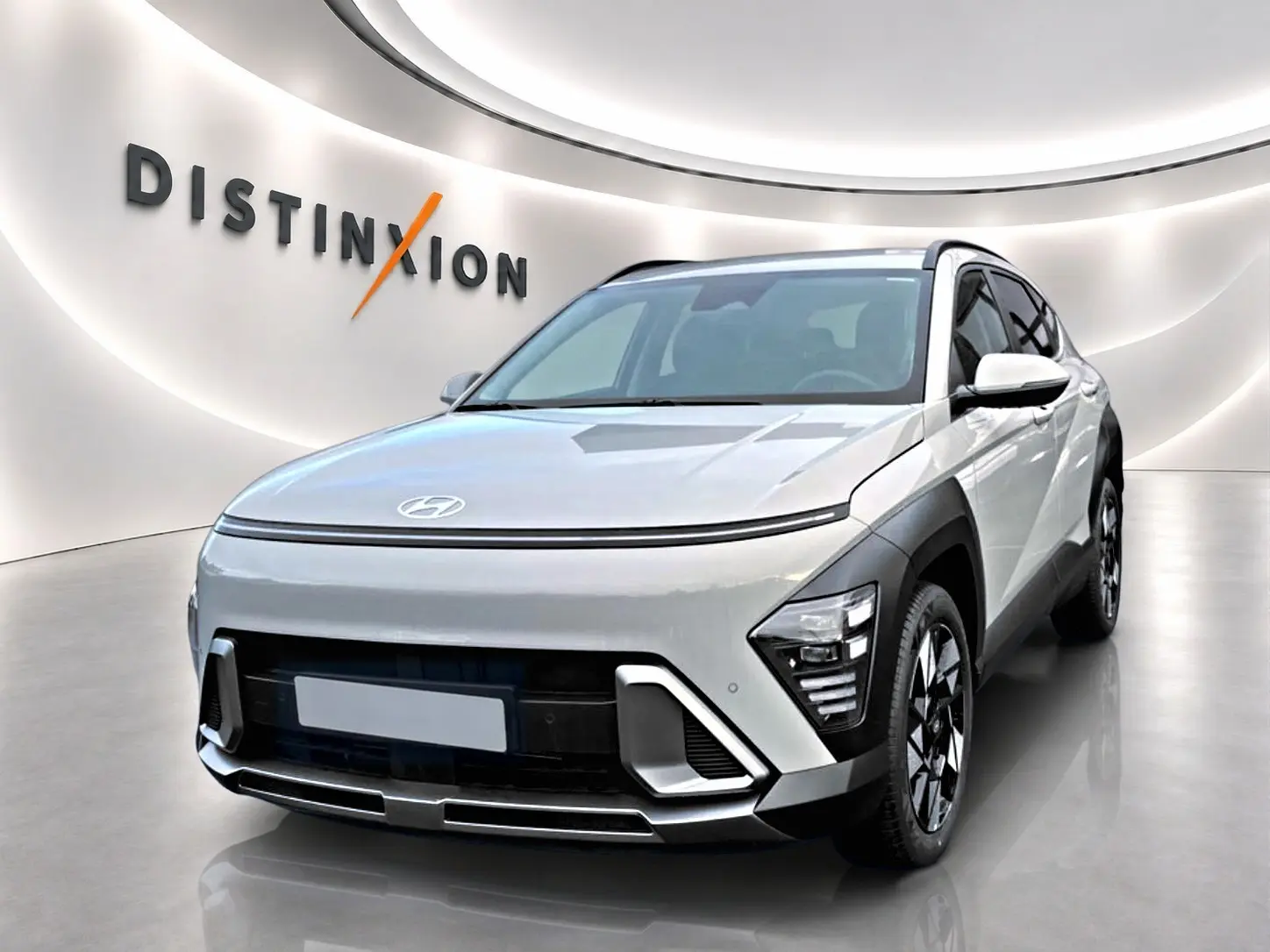 Vue 3/4 avant d'un Hyundai Kona gris avec calandre fermée et jantes alliage noires et argentées dans un showroom.