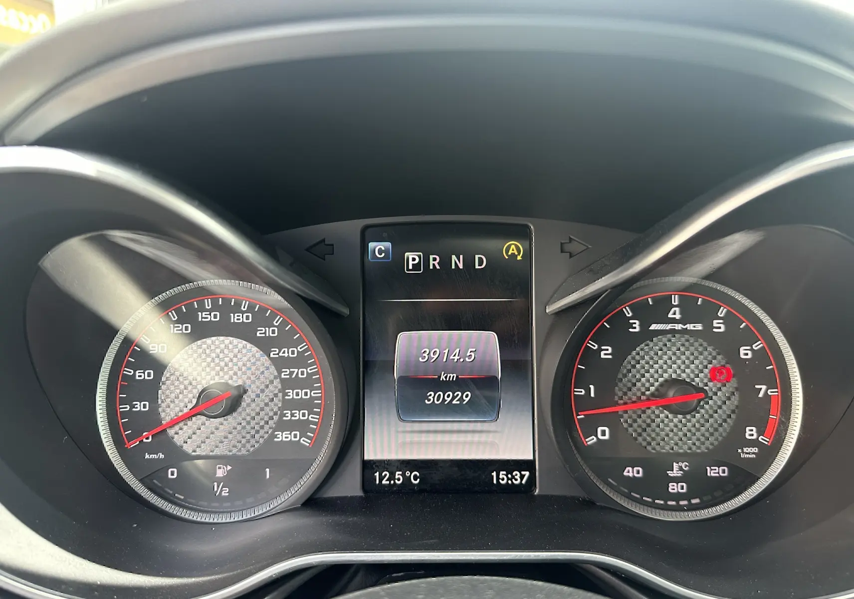 Tableau de bord du Mercedes AMG GT 2015, affichage digital central avec compte-tours et vitesse en carbone.