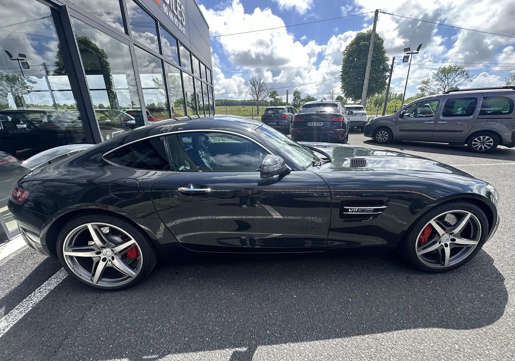 Vue de profil côté gauche d'une Mercedes AMG GT gris foncé avec freins rouges et jantes sportives cinq branches.