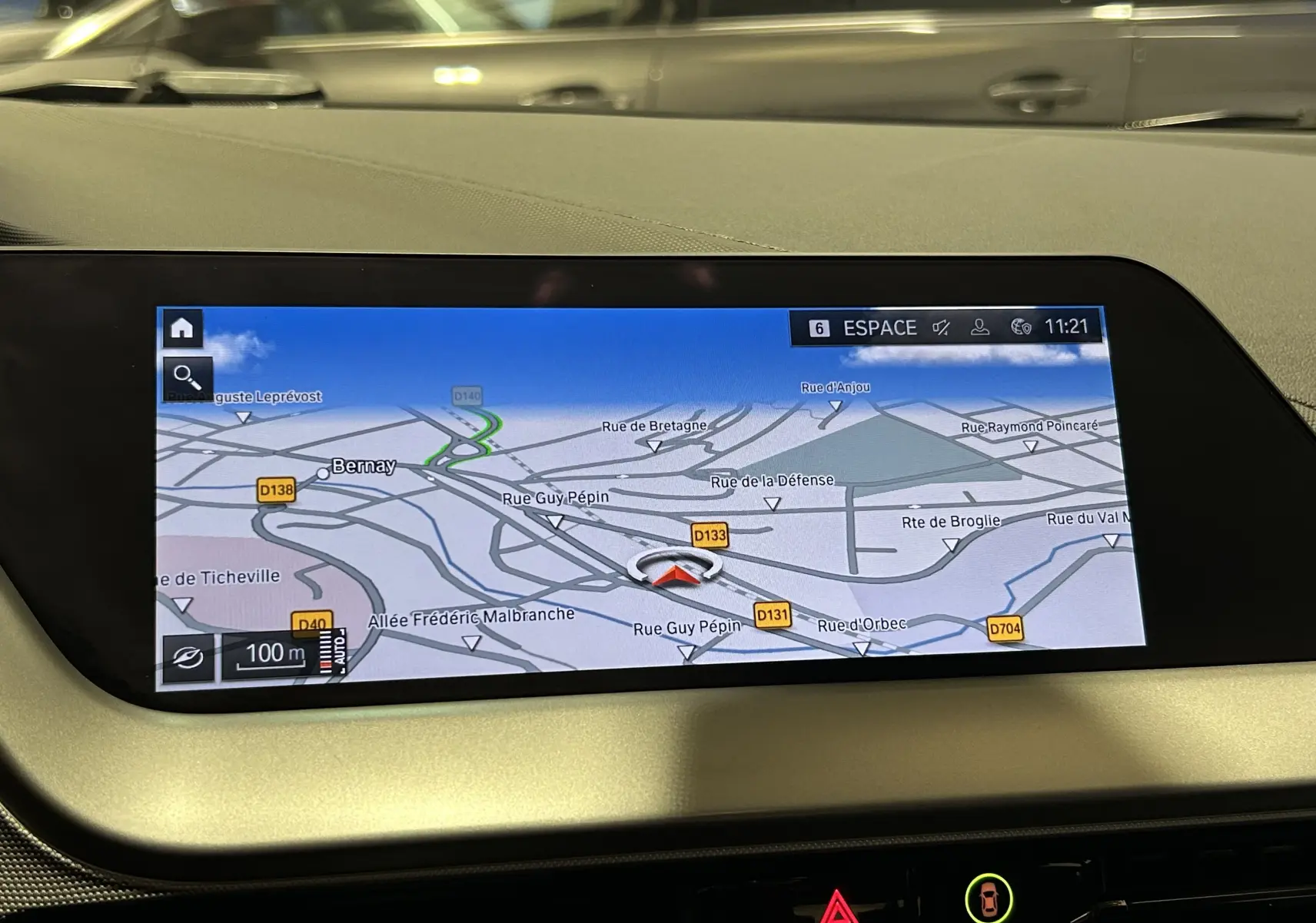 Écran GPS intégré au tableau de bord d'une BMW Série 1 16d noire, affichant une carte routière détaillée.