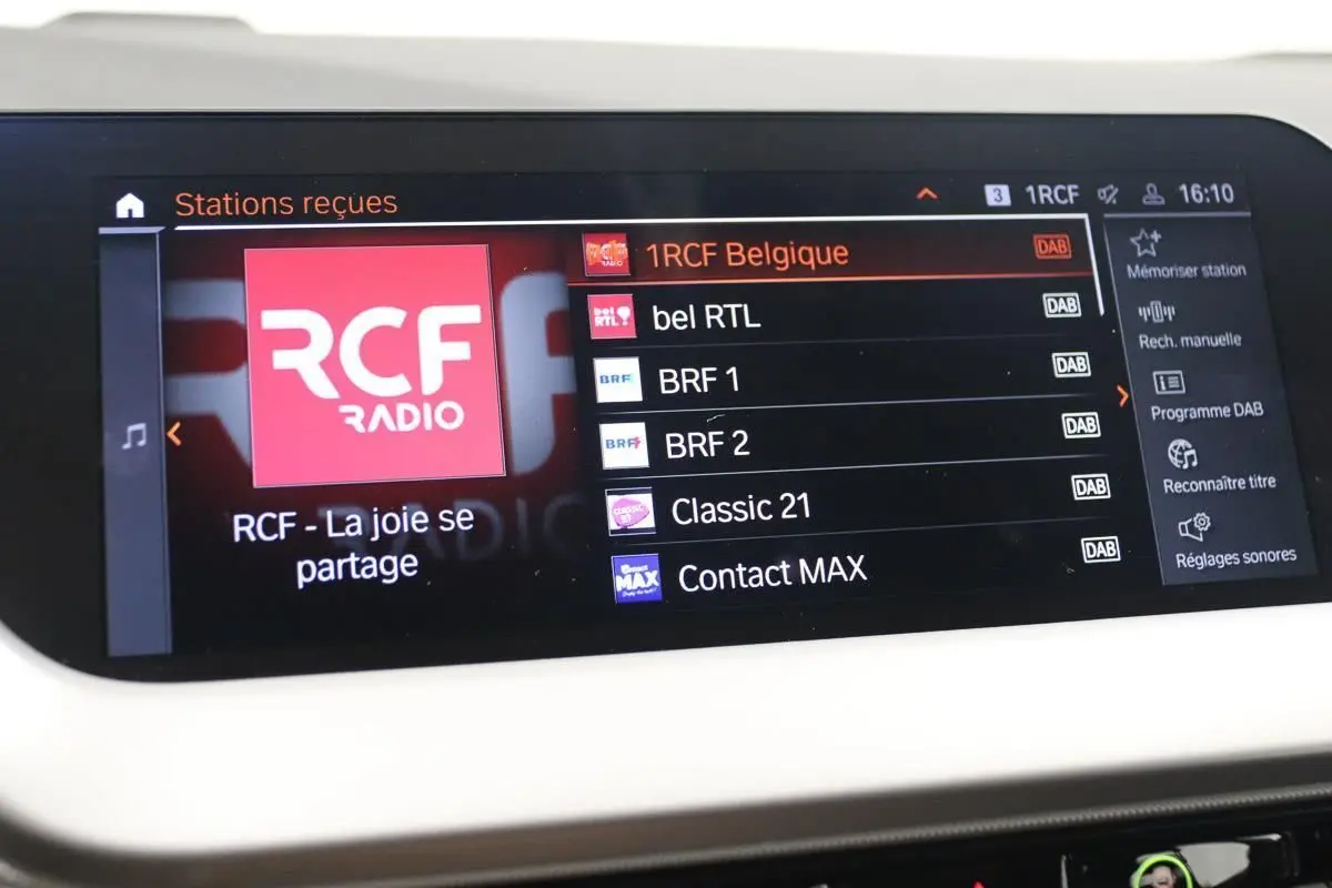 Écran tactile intérieur du système GPS de la BMW Série 1 16d 2023 affichant les stations radio numériques.